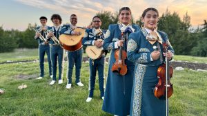 Members of Mariachi Estrella wear blue and white mariachi uniforms and hold instruments.